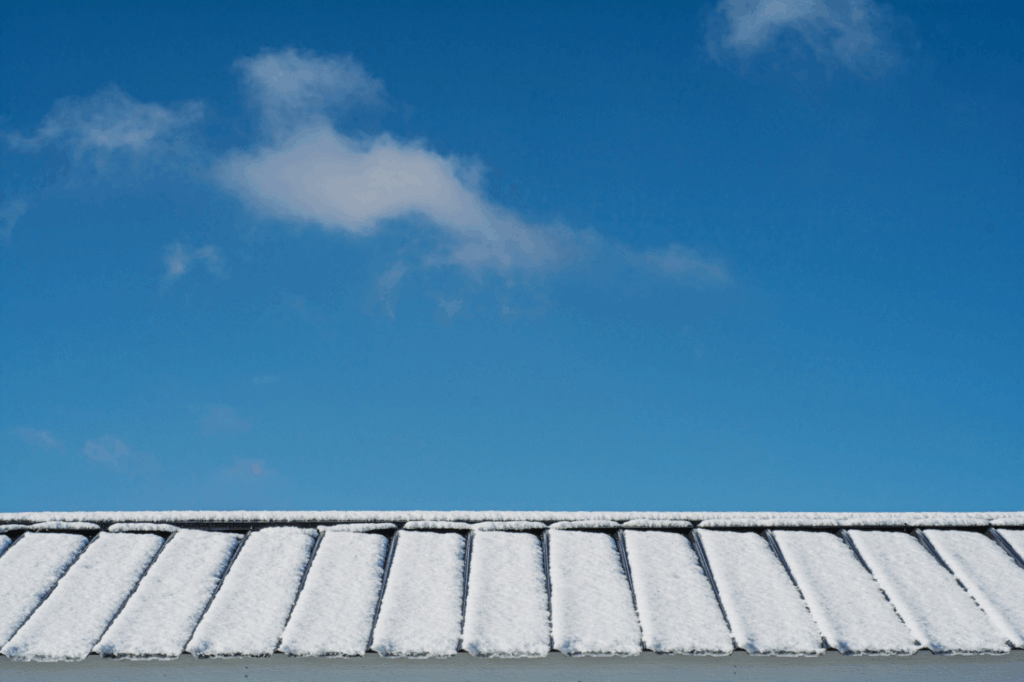 metal roof covered in snow with blue sky