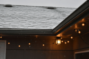 a snow-covered roof with a lamp and lights hanging below