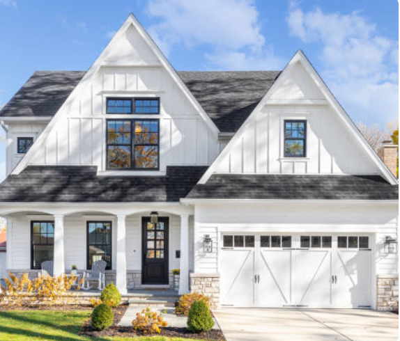A large modern house with a garage and modern shingles. 
