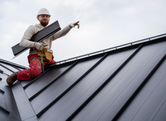 A person sitting on the roof placing metal roofing equipment.
