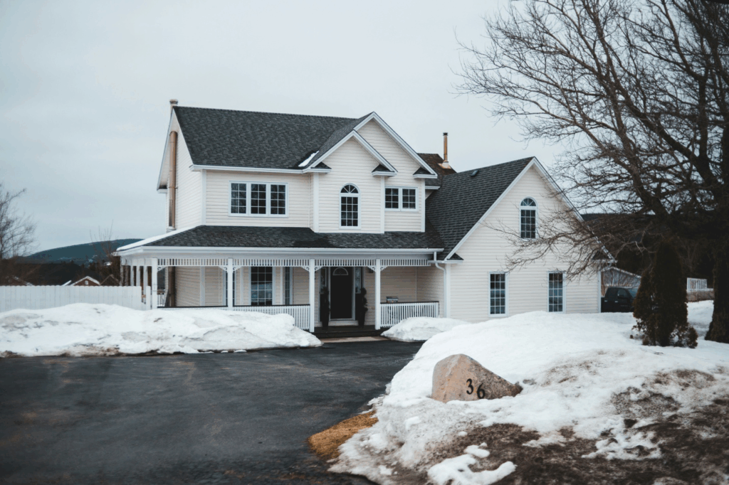 a house with a shingle roof, surrounded by snow