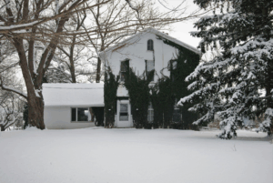 a house surrounded by and covered in snow
