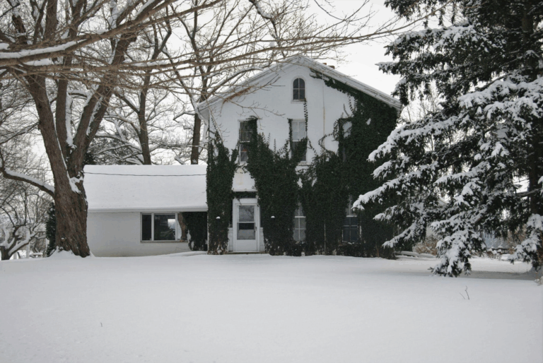a house surrounded by and covered in snow